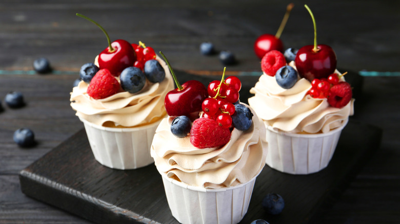 Τρία παγωμένα cupcakes με φρέσκα κεράσια, σμέουρα, bluebarries και βακκίνια στην κορυφή